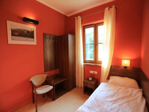 a bedroom with red walls and a bed and a window at Pensjonat Bajdarka in Suraż