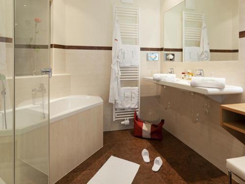 a bathroom with a tub and a sink and a shower at Wohlfühl & Genusshotel Felsenhof in Bad Kleinkirchheim