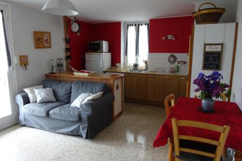 Una sala de estar con un sofá azul y una cocina. en L'aligier - Les gites de Pierregras, en Vals-les-Bains