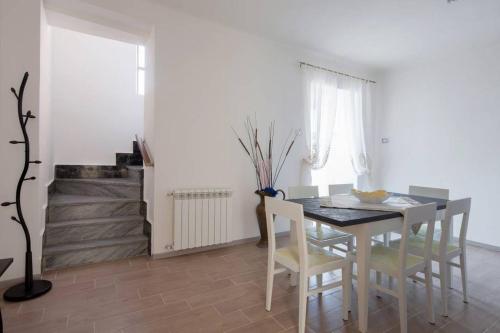 a white dining room with a table and chairs at Casa Sterinella in Follo Alto