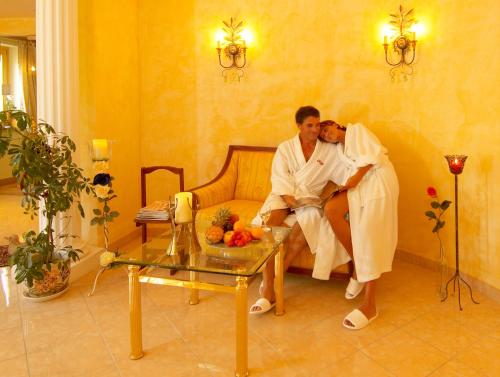 two men sitting on a couch in a living room at Wohlfühl & Genusshotel Felsenhof in Bad Kleinkirchheim