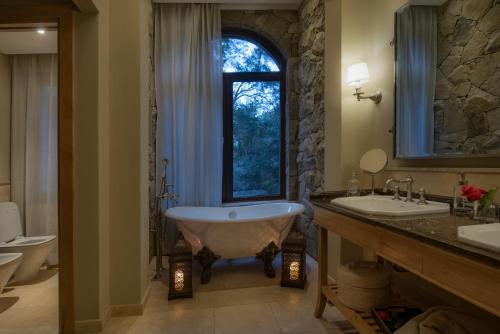 a bathroom with a tub and a sink and a window at Villa Beluno Hotel & Spa in San Carlos de Bariloche