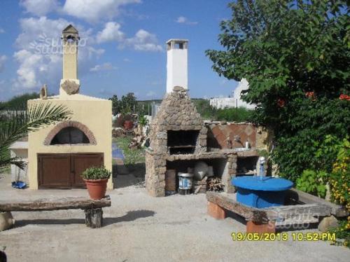 een patio met een stenen oven, een tafel en een bank bij Bungalow a Triscina di Selinunte in Triscina