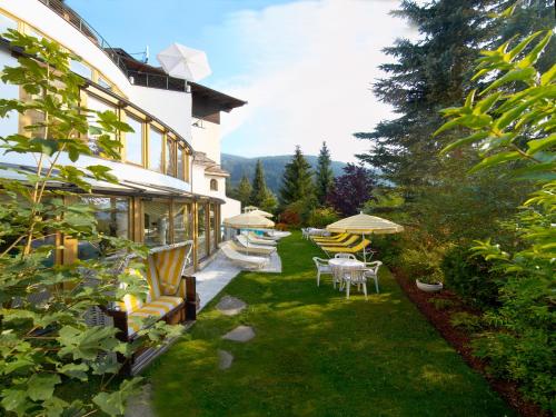 a yard with chairs and tables and umbrellas at Wohlfühl & Genusshotel Felsenhof in Bad Kleinkirchheim