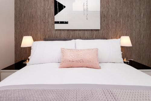 a bedroom with a white bed with a pink pillow at No. 6 Apartment in Inverness