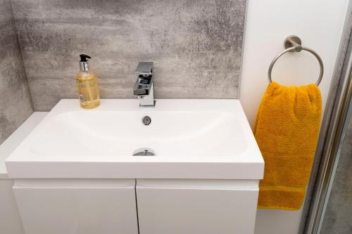 uma casa de banho com um lavatório branco e uma toalha amarela em No. 6 Apartment em Inverness