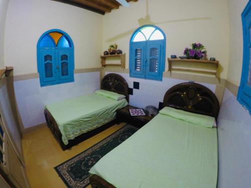 een slaapkamer met 2 bedden en blauwe ramen bij villa tunis village in ‘Izbat an Nāmūs