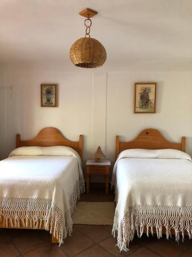 a bedroom with two beds with white sheets and a lamp at Hotel El Portón in Tenancingo de Degollado