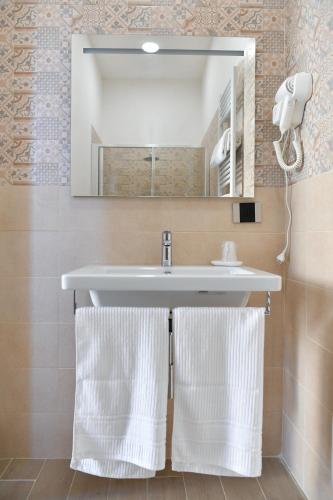 a bathroom with a sink and a mirror and towels at B&B A due passi in Caserta