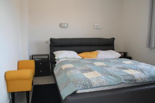 um quarto com uma cama e uma cadeira amarela em Vila Helena em Barbariga