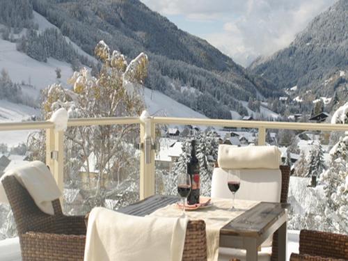 a table with two glasses of wine on a balcony at Wohlfühl & Genusshotel Felsenhof in Bad Kleinkirchheim