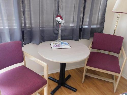 a table with two chairs and a vase with flowers on it at Royal Host Motel in Las Cruces