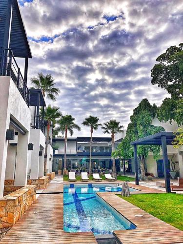 a swimming pool next to a building with palm trees at Marsella 45 in Hermosillo