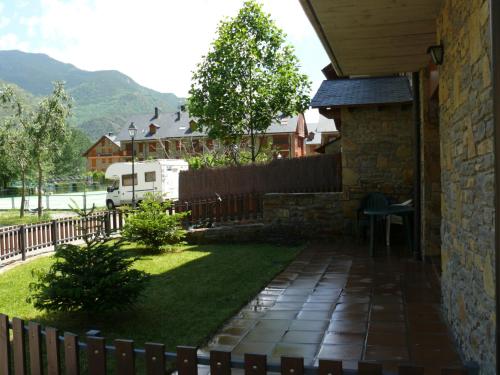 un patio trasero con una valla y una casa en Apartamentos wifi Baqueira & Aigüestortes con jardín privado, en Esterri d'Àneu