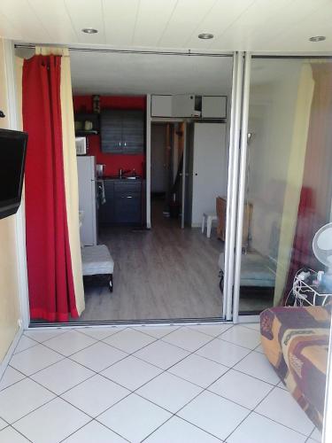 Il comprend un salon avec un rideau rouge et une cuisine. dans l'établissement Appartement 2 pièces Cap d'Agde, au Cap d'Agde