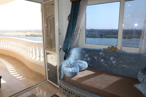 Sofá azul sentado en una habitación con ventanas en Maadi, Direct Nile river View From all Rooms en El Cairo