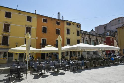 grupa stołów i krzeseł z parasolami w obiekcie Aurora Tiny Apartment w mieście Zadar