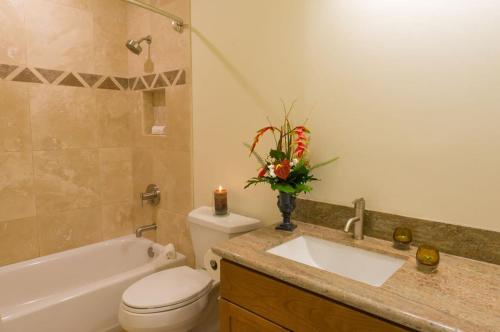 a bathroom with a toilet and a sink with a candle at Puamana 4D Golf Courses Condo in Princeville