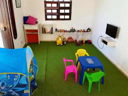 Cette chambre dispose d'une table, de chaises et d'une télévision. dans l'établissement Hostel Praia Centro Itanhaém, à Itanhaém