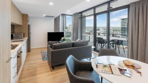 a living room with a couch and a table with chairs at Avani Adelaide Residences in Adelaide