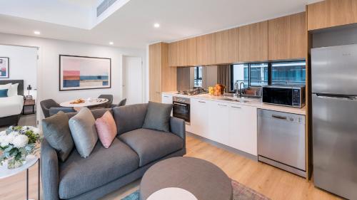 a living room with a couch and a kitchen at Avani Adelaide Residences in Adelaide