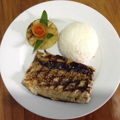 a white plate with a piece of meat and rice at West Atlantic Inn in Concepcion