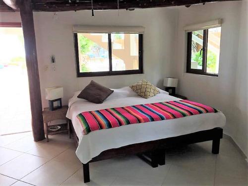 a bedroom with a bed with a colorful blanket on it at CASA TORTUGA, Soliman Bay in Tulum