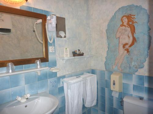 een blauw betegelde badkamer met een wastafel en een spiegel bij Hôtel du Fiacre in Carpentras