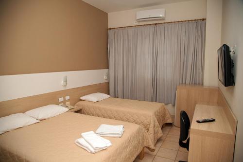 a hotel room with two beds and a television at Apucarana Palace Hotel in Apucarana