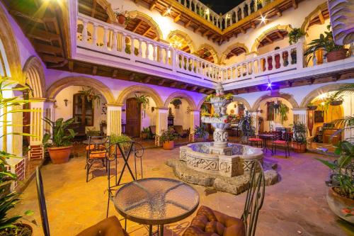 Habitación grande con fuente, mesas y sillas. en Hotel Gran Plaza Euromaya, en Antigua Guatemala