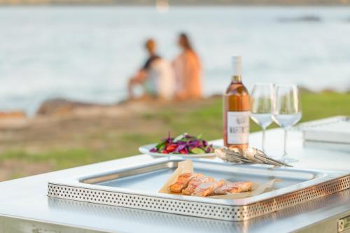 una mesa con un plato de comida y una botella de vino en Ingenia Holidays Eden Beachfront en Eden