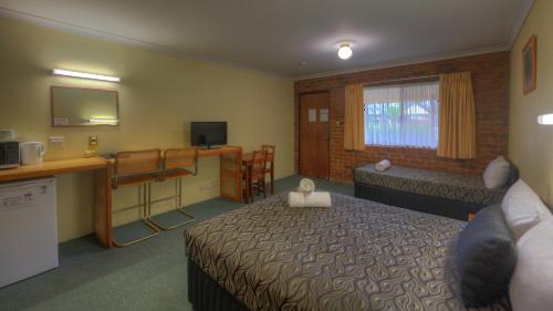 ein Hotelzimmer mit einem Bett und einem Schreibtisch in der Unterkunft Wondai Colonial Motel & Ivory's Restaurant in Wondai