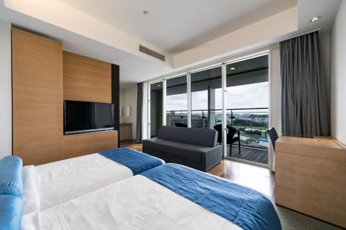 1 dormitorio con 1 cama, TV y sofá en Naha Tokyu REI Hotel, en Naha