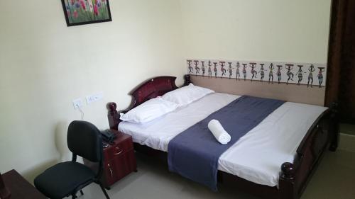 Un dormitorio con una cama y una silla con una botella. en Jai Palace en Chennai