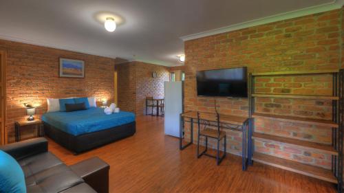 a bedroom with a bed and a brick wall at Wondai Colonial Motel in Wondai