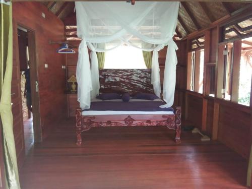 a bed in a room with a window at On The Rocks Bungalows, Restaurant and Jungle Trekking Tours in Bukit Lawang