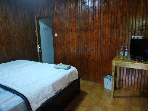 a bedroom with a bed and a wooden wall at Nayta villa Lolai toraja in Rantepao