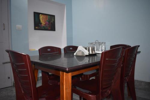 a dining room table and chairs with a black table and chairsuggest at Srishti Homestay in Madikeri
