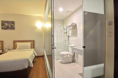 baño pequeño con cama y ducha en Greencity Hotel, en Sungai Petani