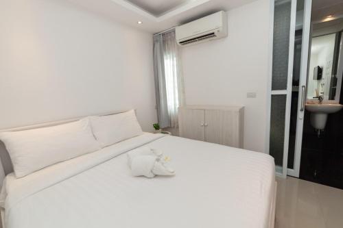 a white bed with a stuffed animal sitting on it at Baanpoon Apartment in Chaweng