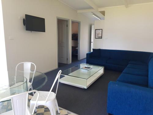 a living room with a blue couch and a glass table at Amaroo Resort in Sussex inlet