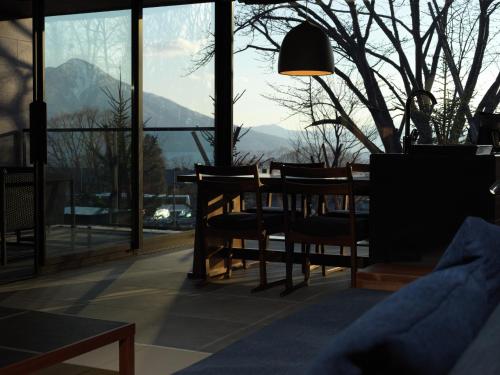 a dining room with a table and chairs and windows at Lake Shikotsu Tsuruga Bessou AO no ZA in Chitose