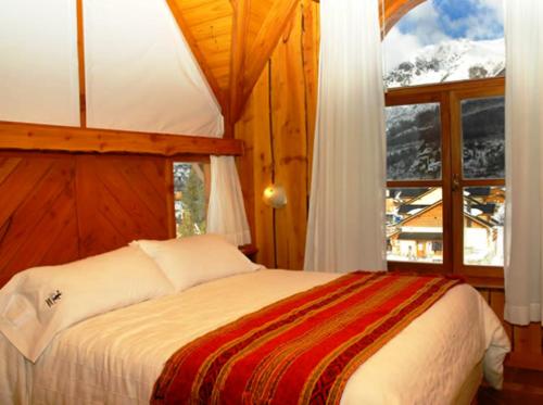 1 dormitorio con cama y ventana grande en Cabañas Aquelarre Catedral en San Carlos de Bariloche