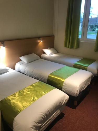 three beds in a room with green and white at Hotel Le Saint Aubin in Gournay-en-Bray