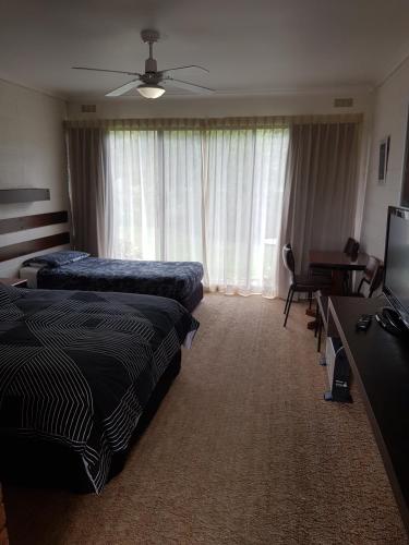 a hotel room with two beds and a desk at Toora Lodge Motel in Toora