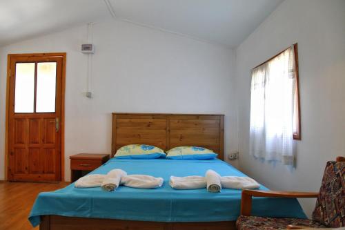 a bedroom with a blue bed with towels on it at KARABURUN KÖYEVİ Pansiyon in Saip