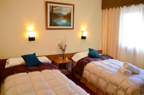 a hotel room with two beds and a window at Hostería Güemes in San Carlos de Bariloche