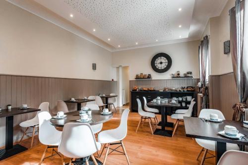 een restaurant met tafels en stoelen en een klok aan de muur bij Hotel Belle Vue Royan in Royan