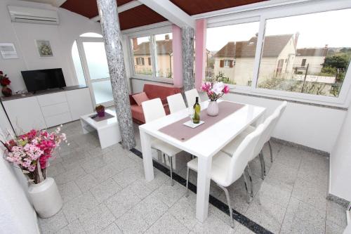 a white dining room with a white table and chairs at Apartments Divna in Rovinj