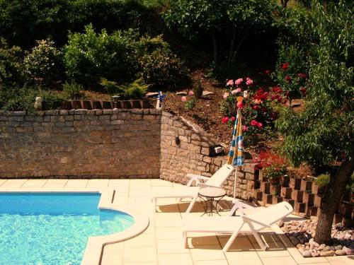 una piscina con 2 sillas de césped y una sombrilla en Millau Aveyron Location Vacances, en Millau